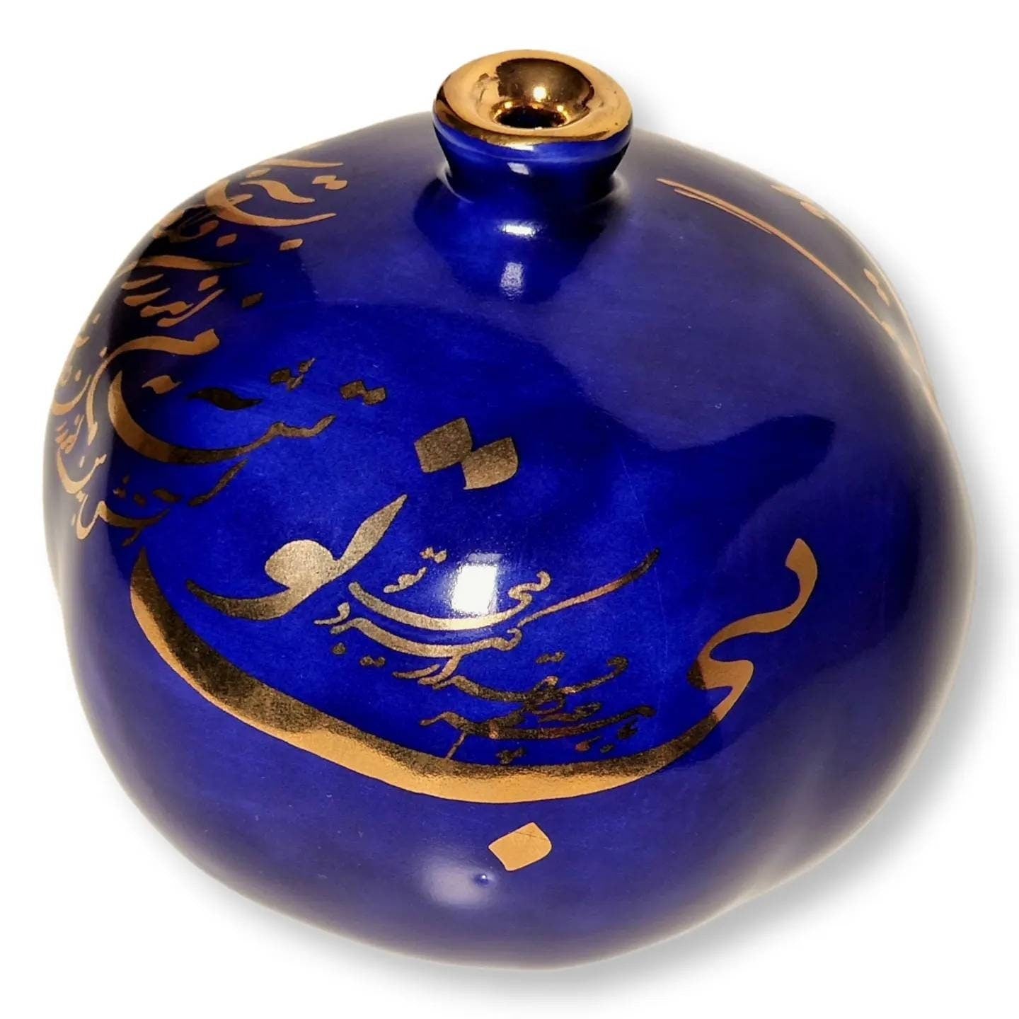 Granada de cerámica hecha a mano, decorada con un elegante diseño de "caligrafía persa Nastaliq" en dorado sobre fondo azul oscuro.