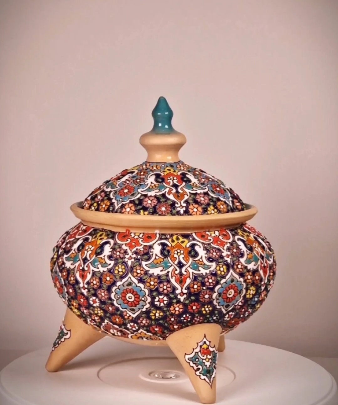Bombonera de cerámica con tres patas decorada a mano mediante el arte persa del "minakari" o esmaltado con un diseño geométrico-floral.