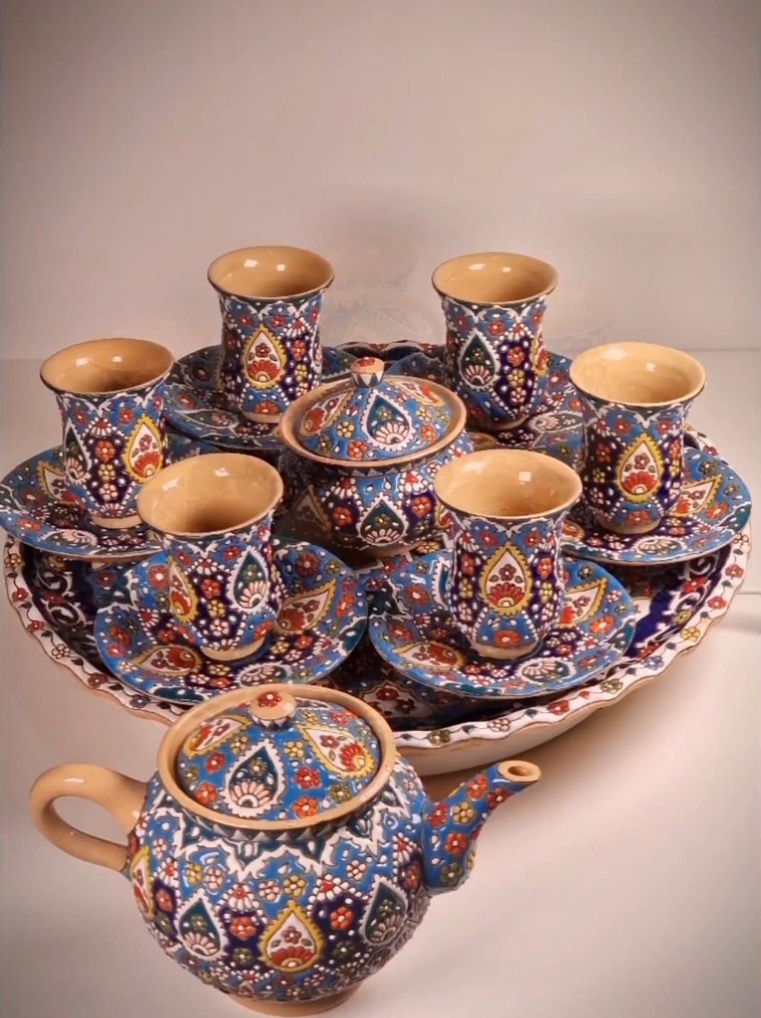 Juego de té de cerámica decorado a mano mediante el arte persa del "minakari" o esmaltado con un colorido diseño en relieve sobre fondo azul