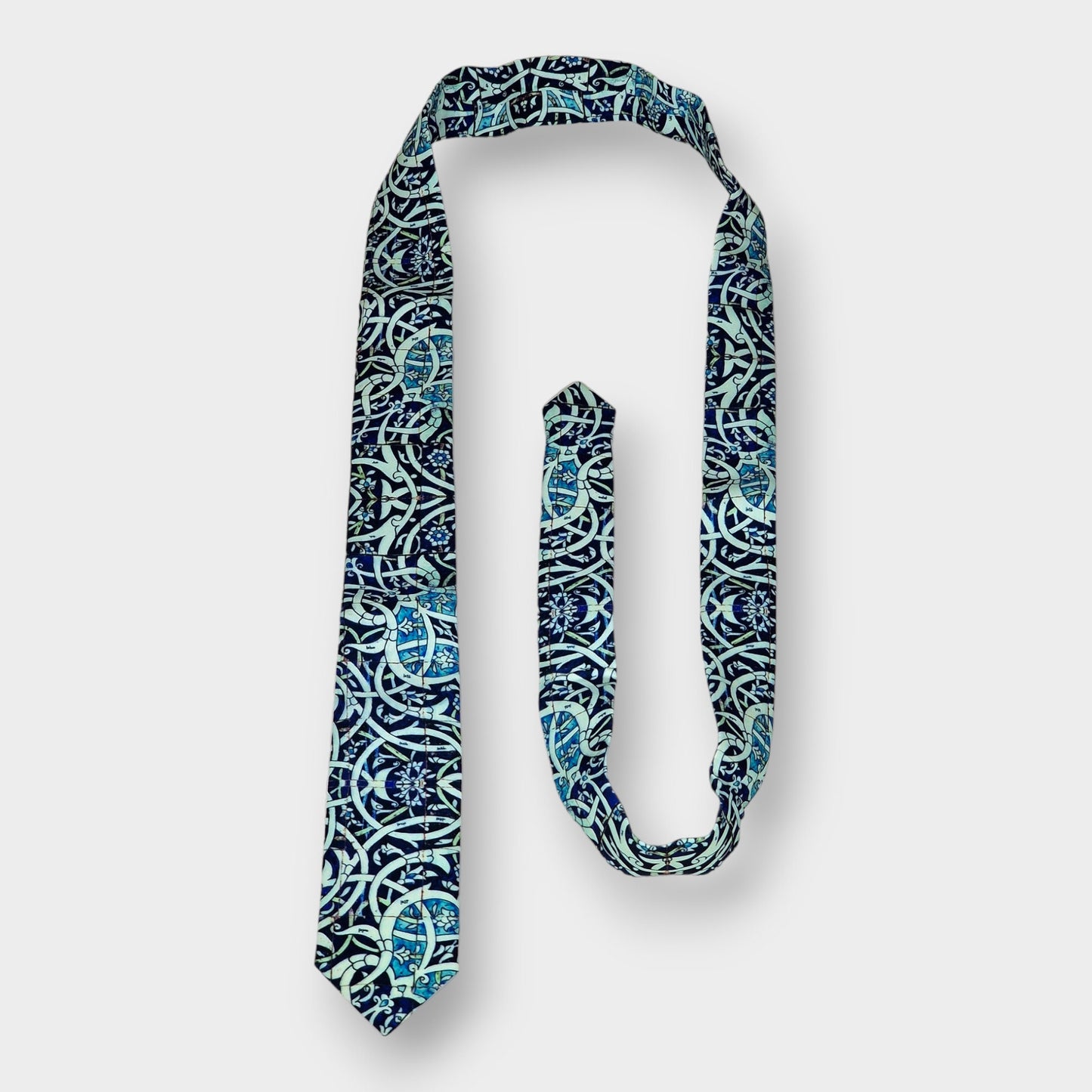 Corbata de crepé de seda inspirada en un diseño de islimi del arte persa sobre azulejos en tonalidades blancas y azuladas.